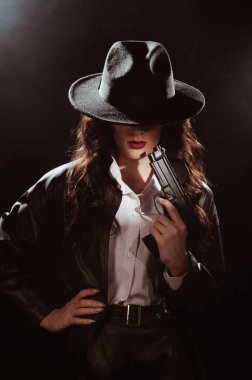 Paltolu ve şapkalı bir kadın dedektifin portresi. Elinde silah vardı. 1950 'lerin dedektiflerinin tarzında bir kara dram portresi.