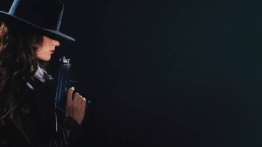 Paltolu ve şapkalı elinde silah olan bir kadın dedektifin silueti. Kopyalayacak bir yer. 1950 'lerin dedektiflerinin tarzında bir kara dram portresi.