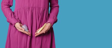 Genç bir kadın, midesinde tampon ve silikon bir adet bardağı tutuyor. Regl döneminde kadınlar için çeşitli hijyen ürünlerinin ellerinde, yakın plan. Metnin için bir yer