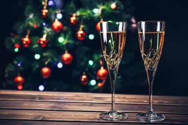 Şampanya kadehleri arka planda dekore edilmiş Noel ağacı. Yeni Yıl