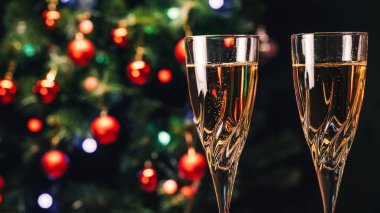 Şampanya kadehleri arka planda dekore edilmiş Noel ağacı. Yeni Yıl