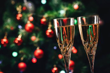 Şampanya kadehleri arka planda dekore edilmiş Noel ağacı. Yeni Yıl