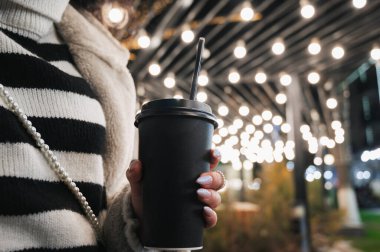 Şehir ortamında elinde bir bardak sıcak içecekle bir kadının ellerine yakın çekim. Kışın açık hava aktiviteleri. Kış Noel 'i ve görüntü