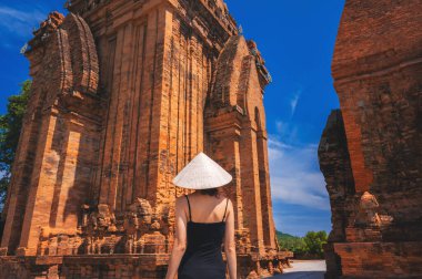 Vietnam 'da geleneksel Non La şapkası takan bir kadın turist. Nagar Cham 'den Towers. Asya 'da seyahat kavramı.