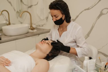 Kadın masajcı kadının elleri, kadın müşterinin yüz derisine masaj yapıyor. Güzellik tedavi konsepti