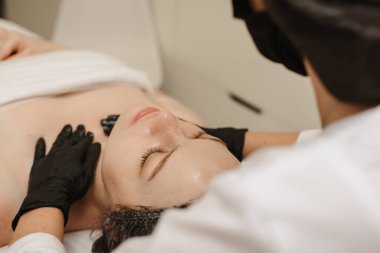 Nitelikli bir masajcı kadının yakın plan fotoğrafı. Kadın müşteriye el masajı yapıyor. Yüz derisi.