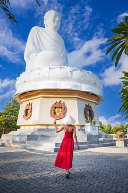 Kırmızı elbiseli bir turist kadın ve Vietnam 'ın başkenti Nha Trang' da güneş gününde Buda 'nın arka planında geleneksel bir Vietnam şapkası.