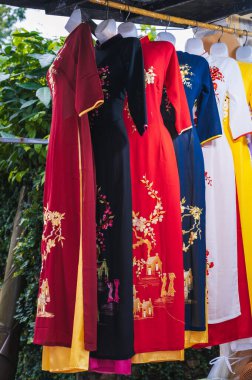 Etnik kültürün parlak Asya kıyafetlerini giyen mankenler. Dükkanlar ve moda endüstrisi. Hoi An, Vietnam 'daki açık hava butik vitrini.
