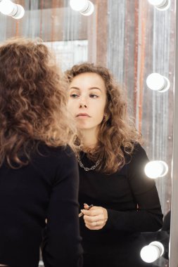 Güzel kız aynaya bakarken kaşları rötuş bir makyaj yapıyor.