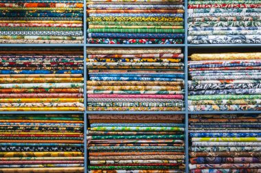 A close-up view of a folded bright and colorful fabric colors in the display of a retail store or atelier in Hoi an clipart