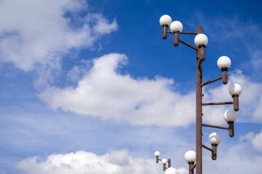 Çok sayıda küre ile süslenmiş şık bir sokak lambası canlı, bulutlu bir gökyüzüne karşı duruyor.