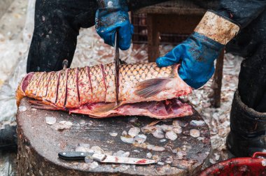 Balık pazarında satıcı sazan balığını küçük parçalara ayırır..