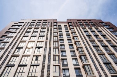 Güneşli bir günde mavi gökyüzünün altında modern bir apartmanın düşük açılı bir görüntüsü.