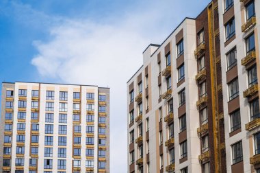 Güneşli bir günde mavi gökyüzünün altında birkaç modern apartmanın düşük açılı görüntüsü.