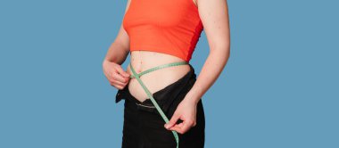 Renkli bir arka planda mezurası olan ince bir kadının midesi. Sağlıklı vücut kavramı, vücut pozitifliği. Panoramik pankart. Boşluk kopyalanıyor