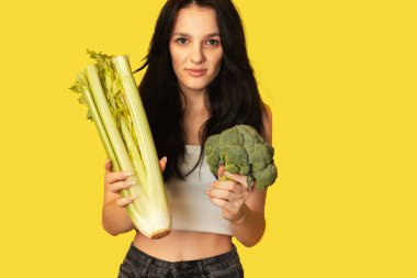 Elinde yeşil sebzeler, brokoli ve kereviz ile gülümseyen ince beyaz kız. Organik sebzeler