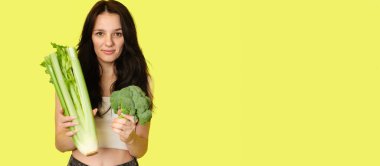 Elinde yeşil sebzelerle gülümseyen ince beyaz kız brokoli ve kereviz, boş alan. Organik sebzeler