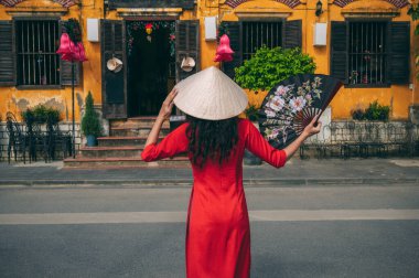 Vietnamlı geleneksel elbiseli genç bayan turist Hoi An Antik kentinde bir hediyelik eşya dükkanına bakıyor..