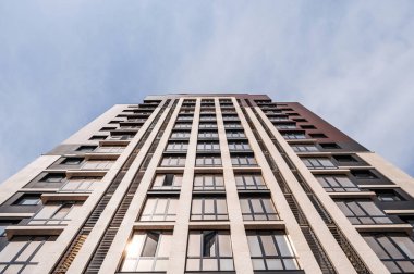 Güneşli bir günde mavi gökyüzünün altında modern bir apartmanın düşük açılı bir görüntüsü.