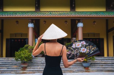 Da Nang 'daki Linh Ung Son Tra pagoda' nın arka planında geleneksel Vietnamlı Non La şapkalı bir turist kadın.