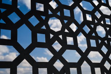 Mavi gökyüzünde kabarık beyaz bulutlar. Pencere ızgarasından bak.