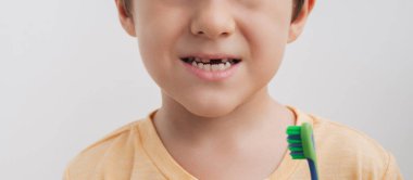 Diş fırçasıyla bebek dişi olmayan küçük bir çocuğun gülümsemesi, yakın plan. Panoramik pankart. Çocuklarda sözlü bakım