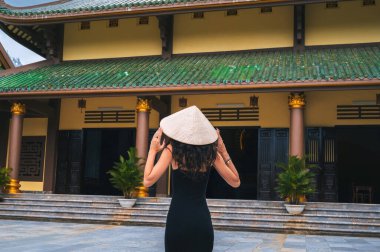 Da Nang, Vietnam 'da Chua Linh Ung. Pagoda arka planında geleneksel Vietnam şapkası takan bir kadın turist.