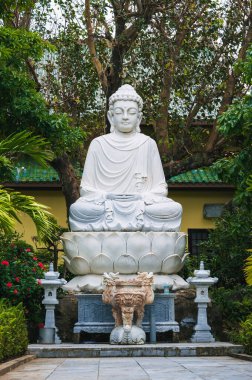 Linh Ung Pagoda 'daki yeşil ağaçların arasındaki beyaz Buda heykeli.