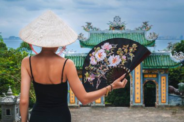 Linh Ung Pagoda Tapınağı 'nı ziyaret eden kadın gezgin, Çince' den tercüme ediliyor. Vietnam şapkalı bir turist ve Da Nang şehrinde gezen bir hayranı var.