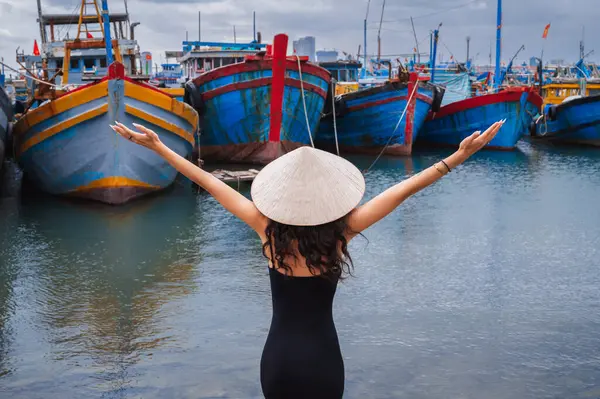 Geleneksel Vietnam şapkası takan bir kadın gezgin Da Nang limanında geleneksel ahşap tekneleri teftiş eder.