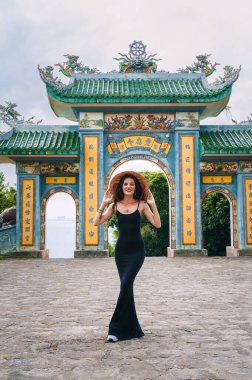 Linh Ung Pagoda tapınağında arka planda kadın gezgin. Vietnam şapkalı bir turist ve Da Nang şehrinde gezen bir hayranı var.