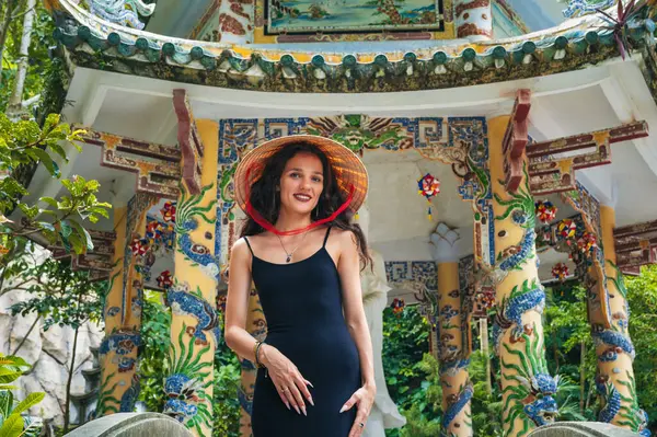 Da Nang 'daki mermer dağlarda Budist tapınağının arka planında geleneksel Vietnam şapkalı bir turist kız.