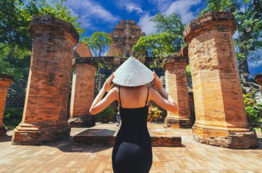 Po Nagar Cham Kuleleri 'nin arka planına bakan bir kadın turist var. Tüm tesisin bir parçası olan tapınak kulesinin yakın görüntüsü..