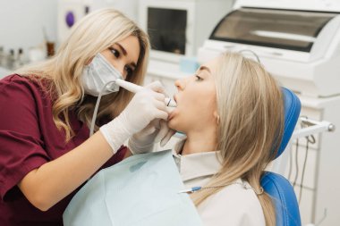 Dişçi, dişinin ağzının tartarını temizlemek için rutin bir ameliyata başlar.