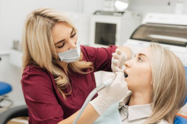 Dişçi, bir kadının dişlerini temizlemek için rutin bir ameliyata başlar.