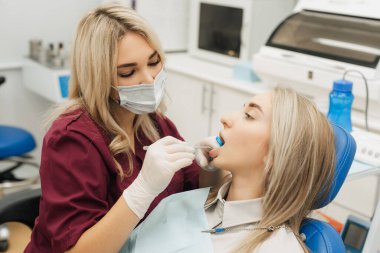 Diş hekimi hastasının dişlerini muayene ediyor.