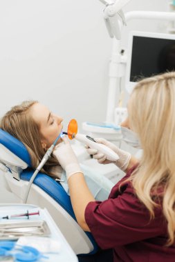 Diş hekiminin dişlerinde ultraviyole lamba kullandığı kısmi görüntü. dikey resim.