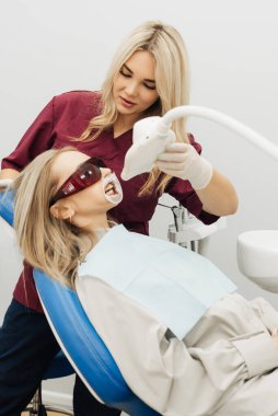 Doktor, ultraviyole lambayla profesyonel diş beyazlatma prosedürü uyguluyor.