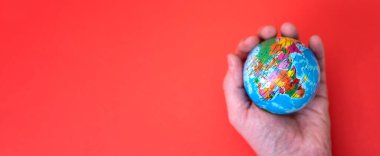 Dünya el ele kırmızı ve kağıt arkaplanda ve metin için boşluk var. Dünyaya duyulan sevgi kavramı.