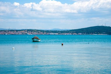 Yazın ve güneşli bir günde bir Türk kasabasının arka planında eski ve küçük bir balıkçı teknesi. Turizm ve seyahat kavramı.