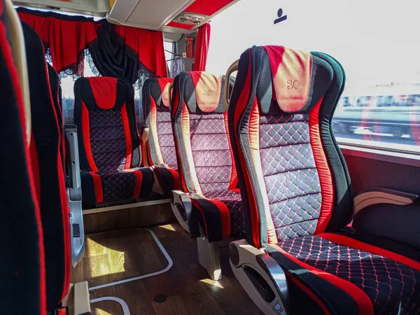 Gündüz gezginler için hoş bir atmosfer yaratan, güneş ışığıyla aydınlatılan, kırmızı ve siyah kapaklı modern otobüs koltukları..