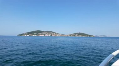 Sakin sularda yelken açan bu deneyim, arka planda parlak mavi bir gökyüzünün altında, tepeleri ve resimsi bir kasabası olan güzel kıyı manzaralarını gözler önüne seriyor..