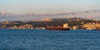 Günbatımında İstanbul Boğazı 'nda dolaşan bir kargo gemisi, arka planda İstanbul' un göz kamaştırıcı ufuk çizgisini gösteriyor. Sıcak ışık, sahnenin güzelliğini ve etkinliğini arttırır..
