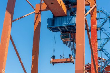 Açık mavi gökyüzüne karşı parlak turuncu yapısı ile bir liman ayarında büyük bir vinç kuleleri.