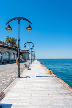 Sakin mavi suların üzerinde uzanan sakin bir rıhtım yolu kapatan klasik lambalarla kaplı. Sahil kenarında sakin bir yürüyüş ve rahatlama ortamı sunuyor..