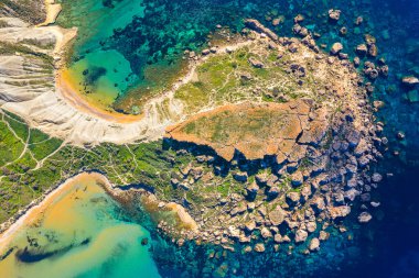 Malta 'nın Gajn Tuffiea kentinin havadan görünüşü, altın hilal kumsalı, turkuaz suları, dramatik kil yamaçları ve dağınık kayalar ve yemyeşil yeşil kıyı şeridinin derin mavi Akdeniz' le buluşmasını gözler önüne seriyor..