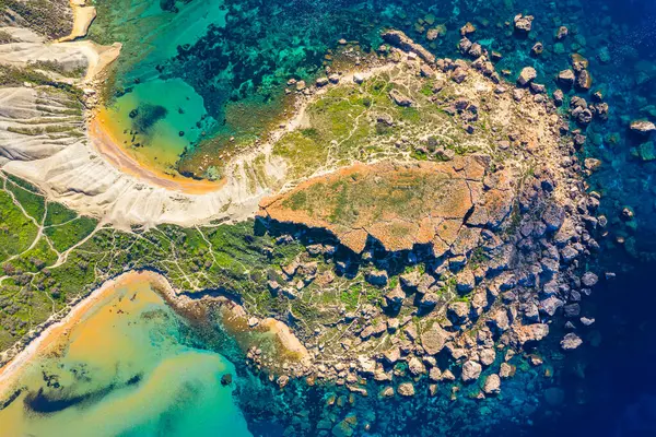 Malta 'nın Gajn Tuffiea kentinin havadan görünüşü, altın hilal kumsalı, turkuaz suları, dramatik kil yamaçları ve dağınık kayalar ve yemyeşil yeşil kıyı şeridinin derin mavi Akdeniz' le buluşmasını gözler önüne seriyor..