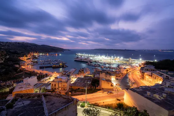 Güneş doğmadan önce Gozo 'daki Gozo Ferry Mgarr Limanı' nda uzun süre görülmüş. Görüntü, feribot terminalinin parlak bir şekilde aydınlatıldığını ve teknelerin rıhtıma yanaştığını gösteriyor..