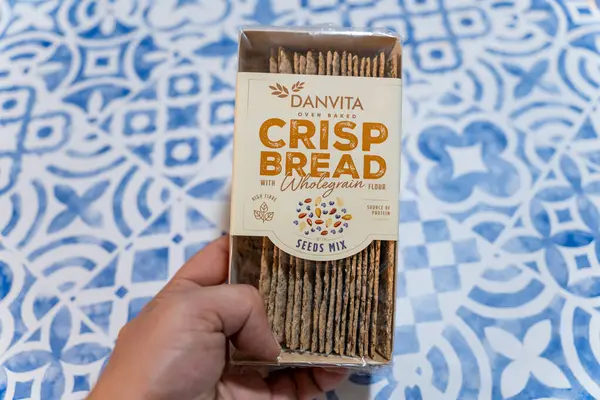 Bir paket Danvita gevreğini tam tahıllı un ve tohum karışımı ile tutarak.