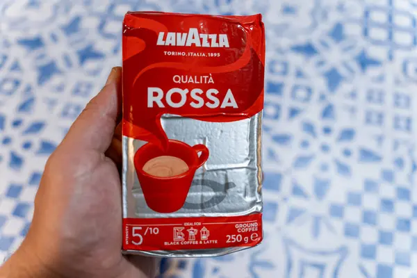 Mavi desenli bir masanın üstünde bir paket Lavazza Qualita Rossa Ground Kahvesi.